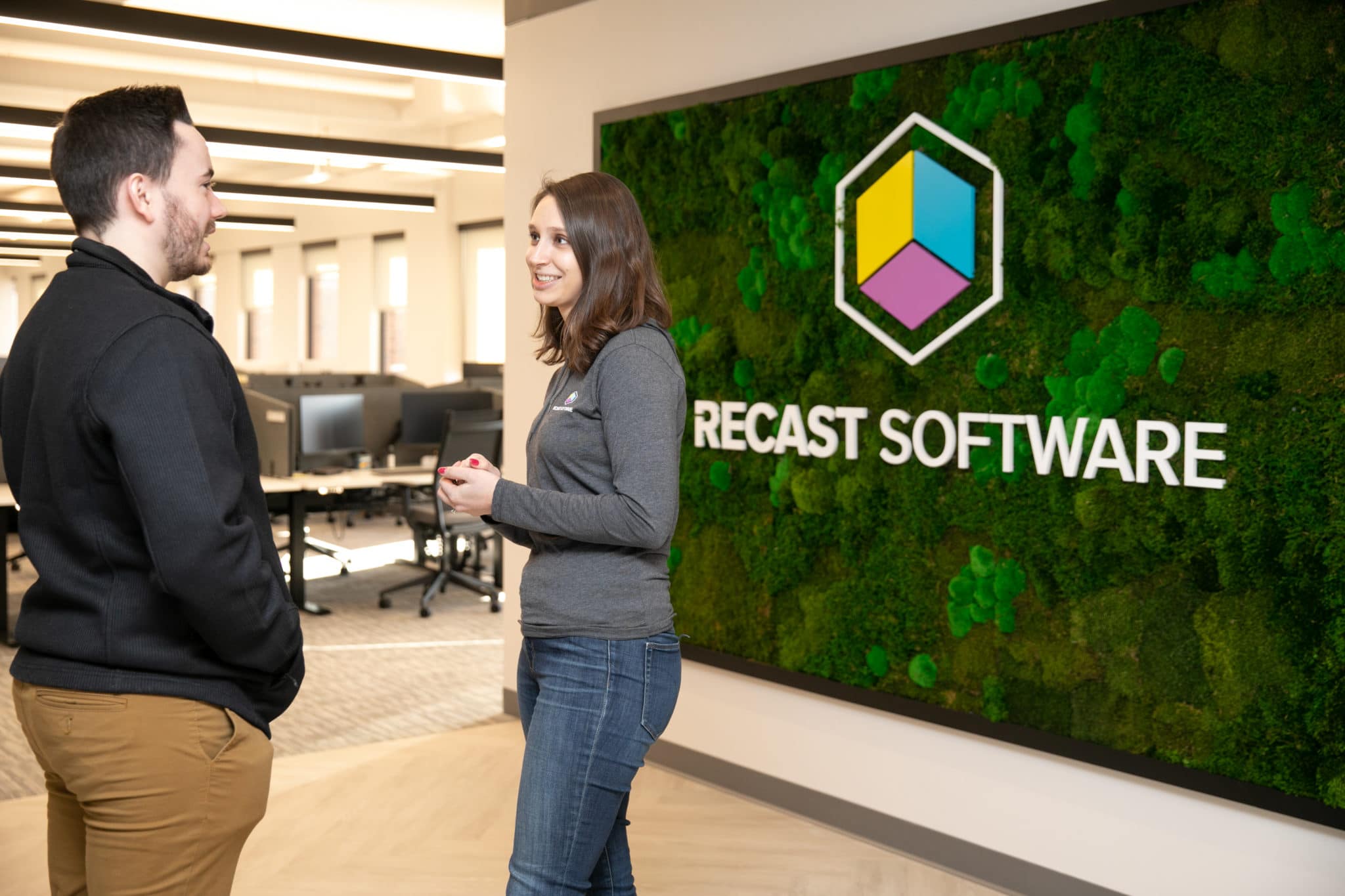 Two Recast associates talking in front of a moss wall.