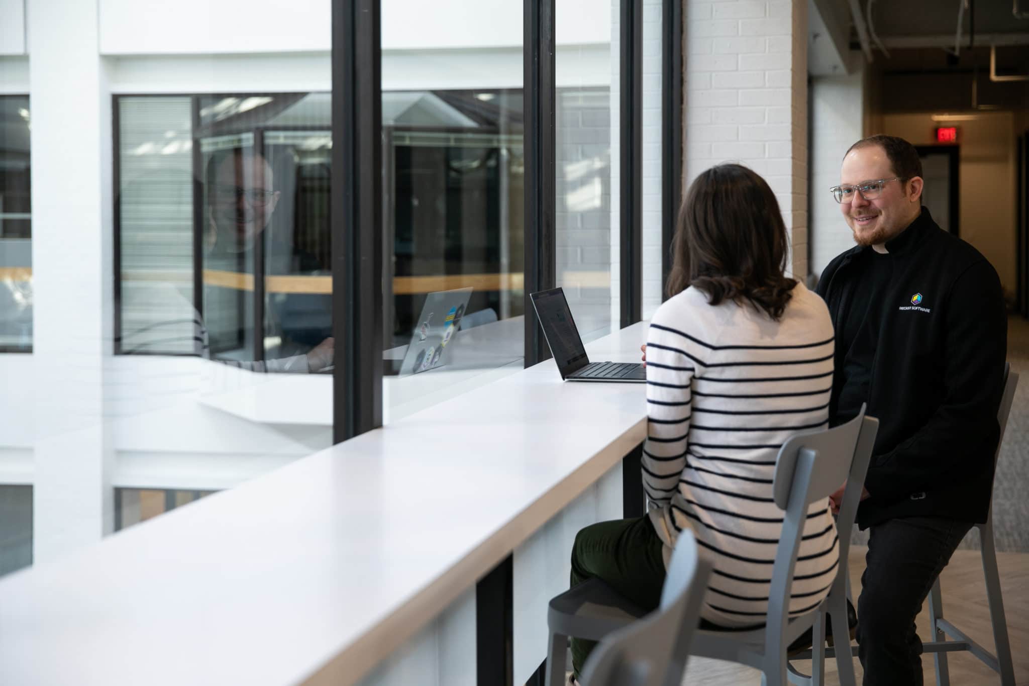 Two associates sitting with a laptop having a conversation.