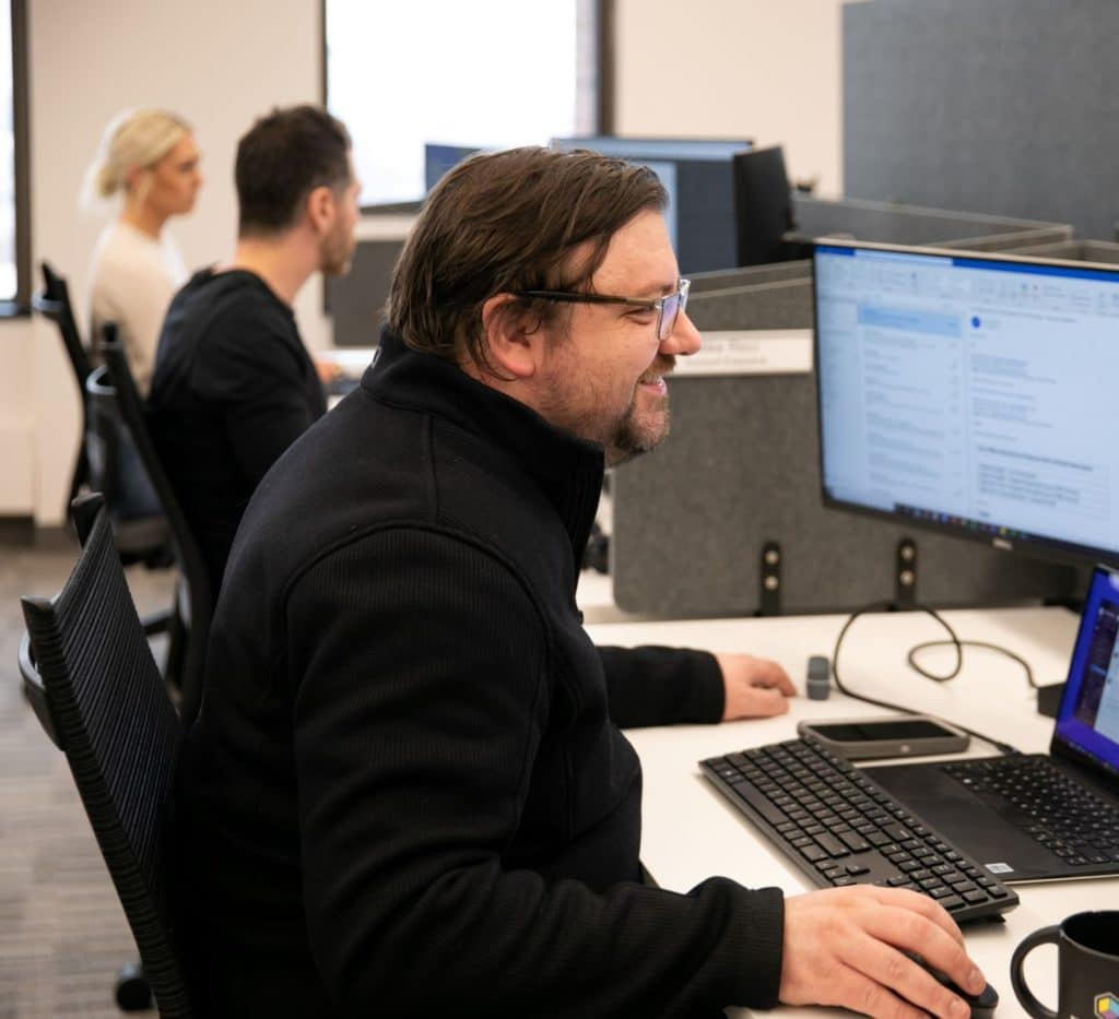 Office setting of three associates working on their computers within Recast Software products.