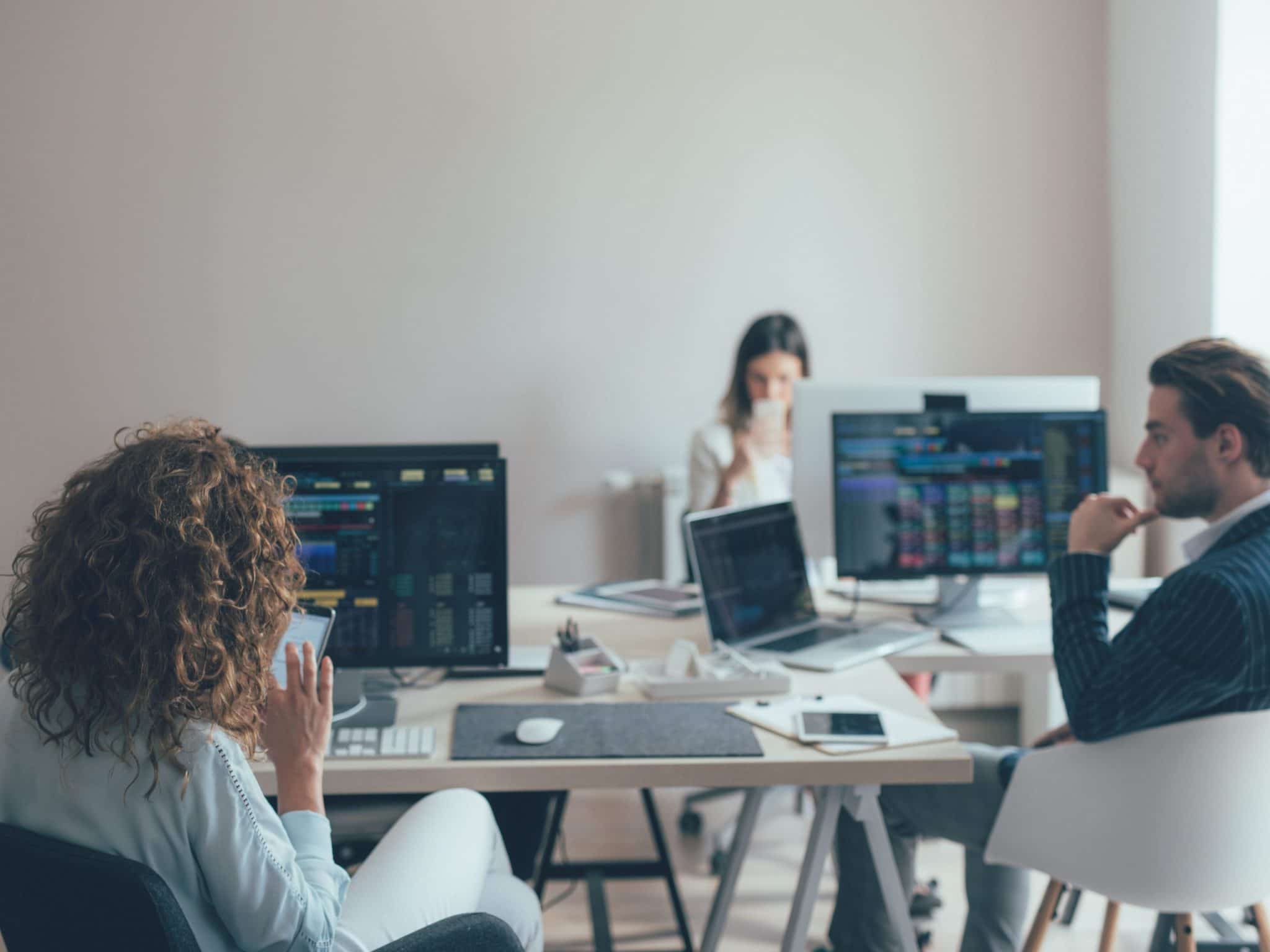 Office setting of three people sitting and looking at their computer monitors which are all supported by Right Click Tools.