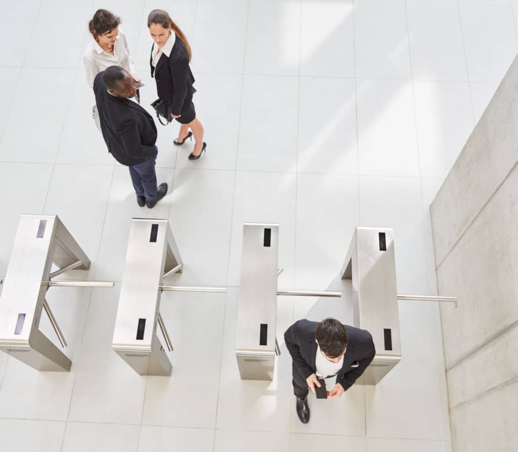 Image of an office building entrance showing one man entering while three are watching.