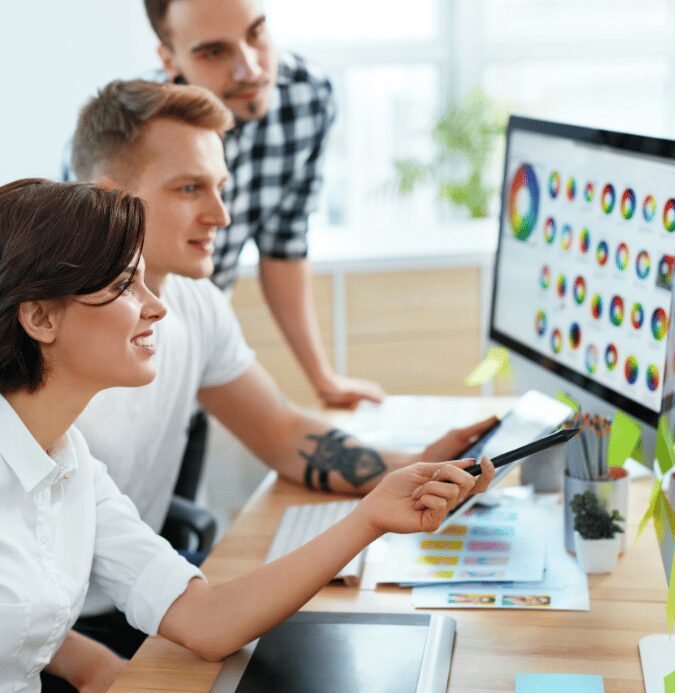 IT experts sitting at a computer looking at various charts and reports regarding efficiencies found with Privilege Manager