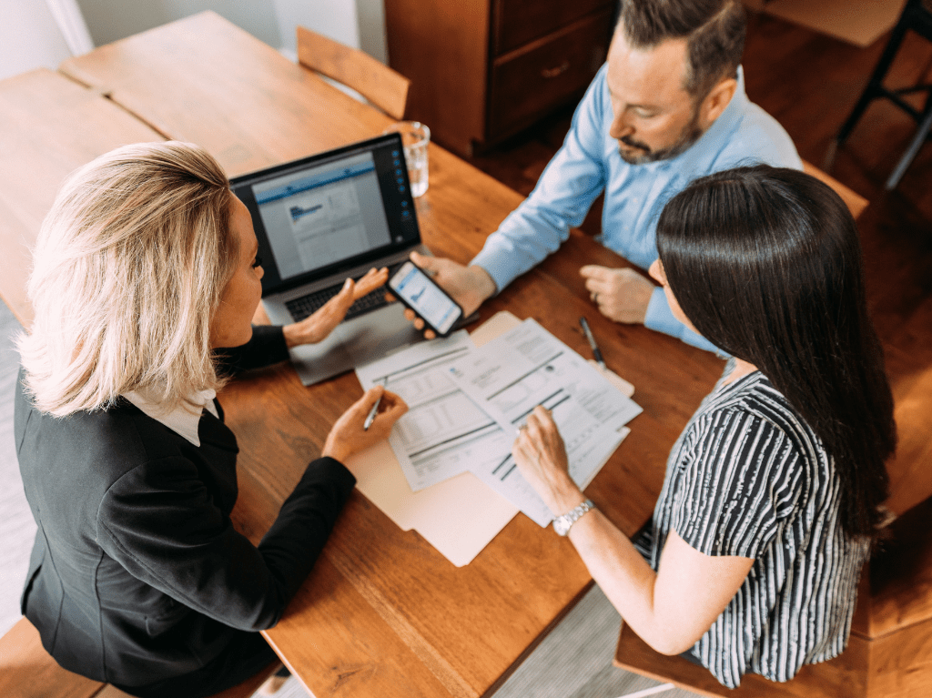 Couple meeting with their financial advisor while looking at a laptop and cell phone.