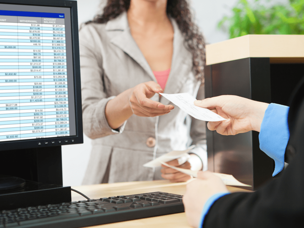 A teller at a bank receiving a paper check.