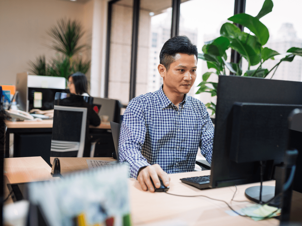 A man sitting at his office desk working on a desktop computer. 