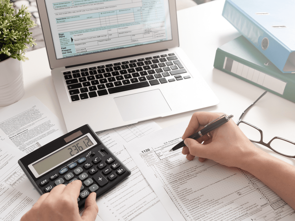 Someone preparing their taxes on a computer using a calculator.