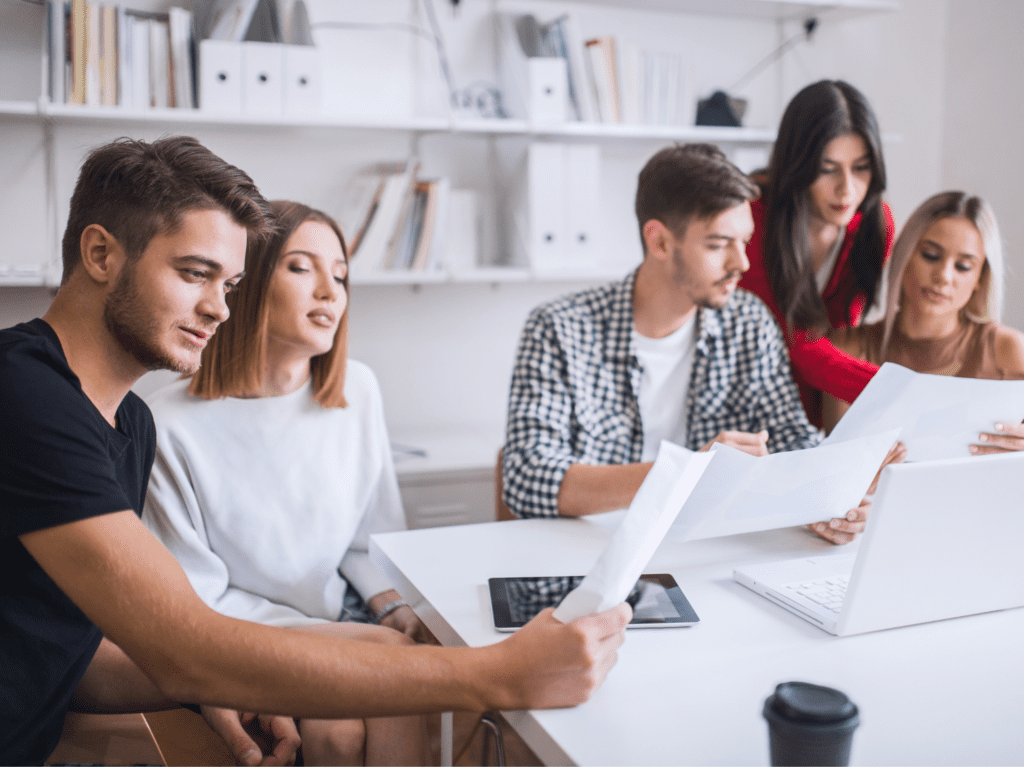 Five people reviewing paper documents together.