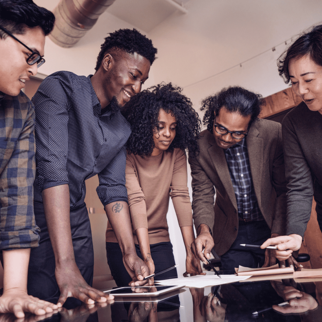 Image of 5 employees surrounding a tablet and work plans.